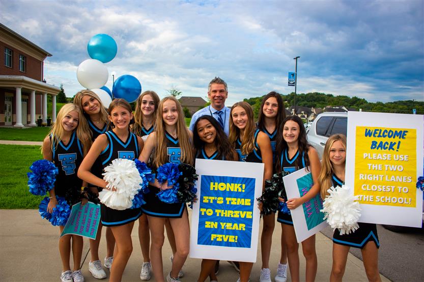 A group of cheerleaders smiles with the Thompson's Station Middle principal